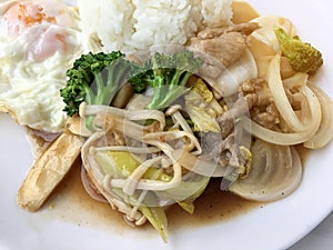 Thai cuisine. Stir-fried colorful vegetables, onion, broccoli, mushroom with meat in white plate with rice and fried egg on white