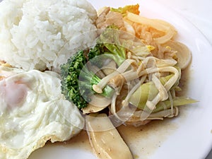 Thai cuisine. Stir-fried colorful vegetables, onion, broccoli, mushroom with meat in white plate with rice and fried egg on white
