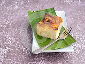 Thai custard cake on banana leaf and spoon on white plate with stone background