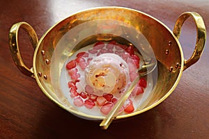 Thai dessert called Tub Tim Grob or Mock Pomegranate in coconut milk served with ice cream in gold brass bowl
