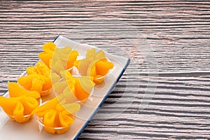 Thai dessert Khanom Thong Yip is placed on a plate over wooden table.