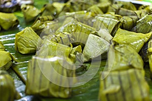 Thai dessert sticky rice, coconut milk and banana wrapped in banana leaves