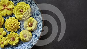 Thai dessert in various flower shaped, warm color tone, yellow mango flavor in antique pattern plate, Sam Pan Nee traditional Thai