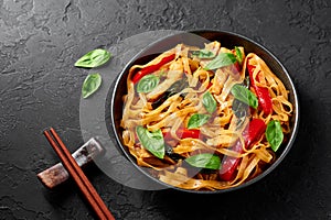 Thai Drunken Noodles or Pad Kee Mao in white plate at black slate background. Drunken Noodles is thai cuisine dish