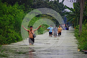 Thai family people natural disaster victims walking wading in water on street of alley while water flood road go receive goods