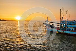 A fishing boat at a pier in the early evening during sunset time