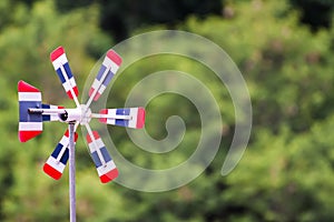 Thai flag wind turbine, blurred natural forest background, the wind blows through, causing the propeller to rotate, free space in