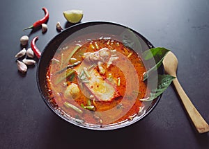 Thai food background concept. Dish of Thailand cuisine. Tom yum soup in black dish and soft focus chilis, galic on table