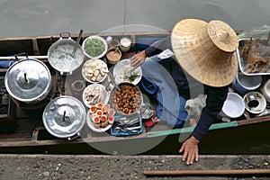 Thai food in floating market, seller with traditional straw hat selling thai food in small boat