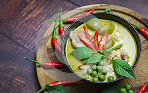 Thai food green curry on soup bowl with ingredient herb vegetable on wooden plate background - green curry chicken cuisine asian