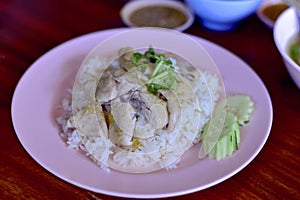 Thai food. Hainanese chicken rice on wood table background. Steamed chicken rice with spicy sauces and chicken soup