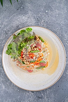 Thai food, Papaya salad on white plate on grey background