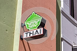 Thai food restaurant sign mounted on a subtle but colorful painted building wall