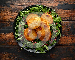 Thai food spicy fish cakes served with pomegranate seeds and wild rocket, arugula salad.