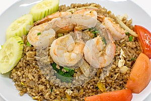 Thai fried rice with shrimps cucumber and scallion on top served on white plate.