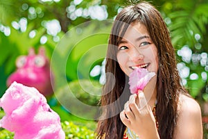 Thai girl is eating pink candyfloss with joy