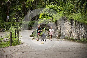 Thai girl and sisters people walking relax and biking bicycle on street at Baan Huay Nam Sai rural countryside village valley hill