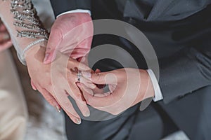 Thai groom putting a wedding ring