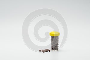 Thai herbal medicine in plastic bottle with modern design and many pills spread on a white background