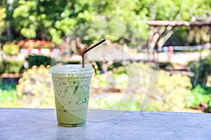 Thai Iced matcha green tea with milk and brown straw on table background