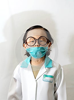 Thai kid boy with glasses in doctor gown or uniform with mask li