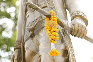 Thai king statue with marigold on sword