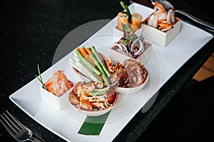 Thai local cuisine, spicy papaya salad or Som Tum with deep fried soft shell crab and spring rolls