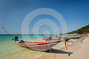 Thai local long tale boats at the beach under clear blue sky