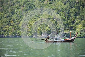 Thai man fisher people sailing wooden long tail boat fishery floating in sea use net catch fishing marine and fish in ocean at Mu