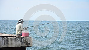 Thai man sitting and fishing or angling in sea