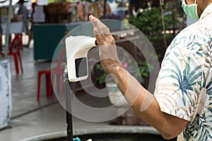 Thai man travelers people use hand scan for check body temp with infrared thermometer before travel visit Local Talad Nam Lumphaya