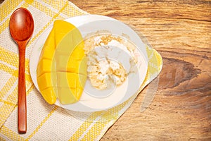 Thai mango and sticky rice with coconut milk desserts on white dish with wooden background. Mango is Thailand`s tropical fruit.