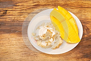 Thai mango and sticky rice with coconut milk desserts on white dish with wooden background. Mango is Thailand`s tropical fruit.