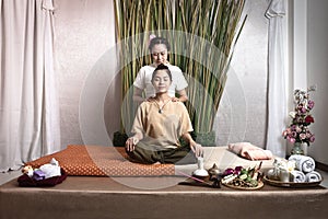 Thai Masseuse doing massage for woman in spa salon. Asian beautiful woman getting thai herbal massage compress massage in spa.She