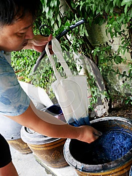 Thai men tie batik dyeing Indigenous Knowledge chemical and liquid dye Mauhom and indigo color in pot at Nonthaburi, Thailand