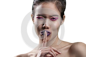 Thai model wears purple lipstick very close shot of mouth and teeth. shot on a white backdrop.