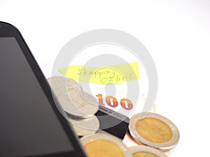 Thai money, 100 baht and coins with credit card, black mobile phone with online shopping business on post it, arrow shape isolated