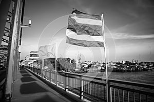 Thai national flag waving in the wind against deep blue sky on Krung Thonburi Bridge at Rajvithi Road Bangkok Thailandn
