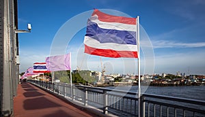 Thai national flag waving in the wind against deep blue sky on Krung Thonburi Bridge at Rajvithi Road Bangkok Thailandn