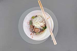 Thai noodle dry vermicelli with porks in tiny white bowl.