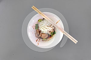 Thai noodle dry vermicelli with porks in tiny white bowl.