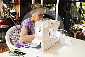 Thai old women working use sewing machine made fabric mask at workshop while Coronavirus COVID 19 outbreak and PM 2.5 Dust