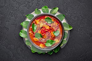 Thai Panang Chicken Curry in black bowl at dark slate background. Phanaeng Curry is Thai Cuisine dish