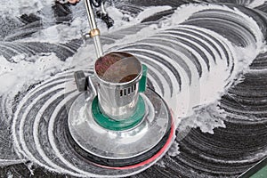 Thai people cleaning black granite floor with machine and chemical