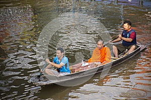 Thai people praying put food and thing offerings to monks procession on boat in tradition of almsgiving at Wat Sai Yai on November