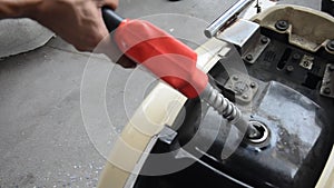 Thai people use gas pump nozzle filling gasoline fuel to tank of motorcycle