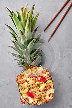 Thai Pineapple Fried Rice or Kao Pad Sapparod dish in pineapple bowl on gray backdrop. Thailand meal. Asian Food