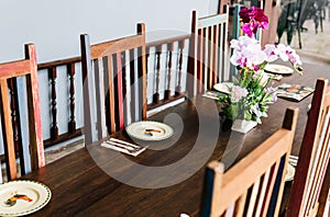 Thai restaurant table with cutlery, plate, glass, napkins and orchids on the table