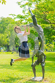 Thai schoolgirl is jumping with statue in park