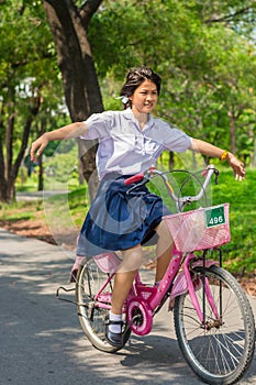 Thai Schoolgirl playing risky on a bicycle, in the park.